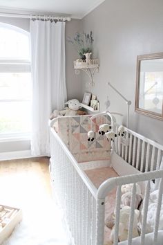 a white crib with stuffed animals in it and a window behind the crib