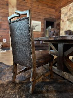 a chair sitting in front of a wooden table with a cowhide rug on it