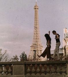 two people are walking near the eiffel tower