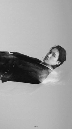 a black and white photo of a young man floating in the water with his head down