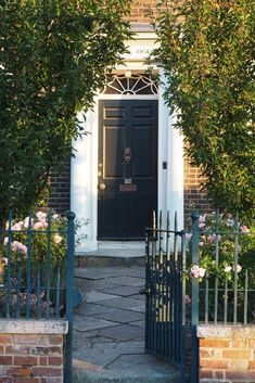 an entrance to a brick building with wrought iron gates and flowers in the foreground