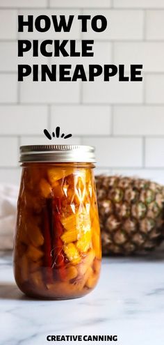 a jar filled with pickle and pineapples on top of a white counter