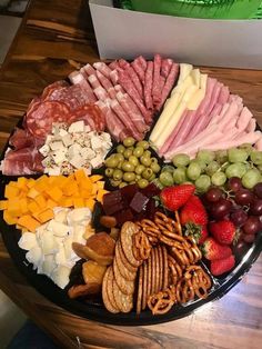 a platter filled with different types of cheeses, crackers and fruit