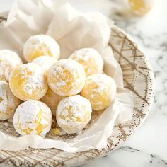 powdered sugar covered donuts in a bowl on a marble counter top with napkins