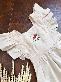 a white dress sitting on top of a wooden floor next to some flowers and grass