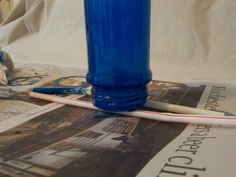 a blue glass sitting on top of a newspaper