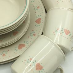 a stack of white plates and cups with hearts painted on the rims, sitting next to each other