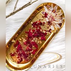 a gold tray filled with red flowers on top of a white table covered in snow