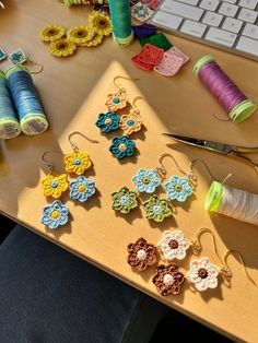 there are many small crocheted flowers on the table next to thread and scissors