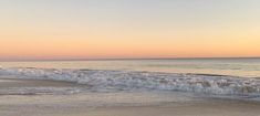 a person riding a surfboard on top of a wave in the ocean at sunset