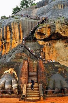 stairs leading up to the top of a large rock formation with people climbing down it