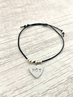 Show your love for NCT (and all subunits!) with this minimalist delicate cord bracelet featuring a hand stamped metal tag and silver glass beads. Choose from a round or heart shaped tag. The bracelet is adjustable up to 8 inches. Please message me if you would like a different size. Each bracelet is handmade and may differ slightly from what is shown in the pictures.  Note: Free shipping does not include tracking. Orders over $35 include free tracked shipping! All orders include a free photocard! Let me know if you would prefer one of your bias or you'll receive a random one. Adjustable Nickel-free Sterling Silver Friendship Bracelets, Minimalist Adjustable Beaded Bracelets With Heart Charm, Minimalist Adjustable Silver Heart Bracelet, Adjustable Heart Shaped Sterling Silver Beaded Bracelet, Casual Adjustable Jewelry With Heart Charm, Simple Adjustable Hand Stamped Jewelry, Adjustable Nickel-free Heart Bracelet For Everyday, Sterling Silver Adjustable Friendship Bracelets, Casual Adjustable Heart Charm Jewelry