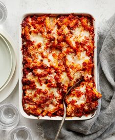 a casserole dish with meat and cheese on it, next to empty dishes