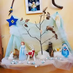 a table topped with figurines next to a tree and other items on top of it