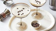 two martinis on a tray with pecans in the middle and one is empty