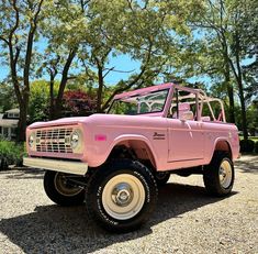 a pink truck parked in front of some trees