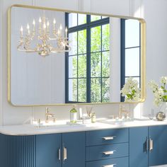 a bathroom with two sinks and a large mirror over it's counter top that has flowers in vases on it