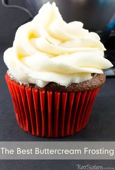 a cupcake with white frosting sitting on top of a table