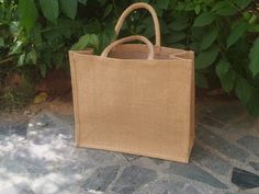 a brown bag sitting on top of a stone floor next to green plants and trees