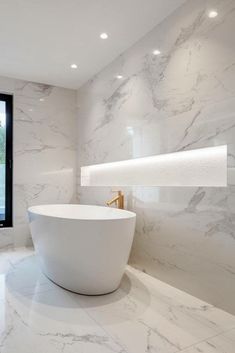 a large white bathtub sitting in the middle of a bathroom next to a window