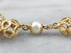 This pretty bracelet is in the Victorian Revival style! Shimmering white pearls alternate with gleaming filigree baubles, creating an ornate look around the wrist. A fun chain tassel charm creates an eye-catching focal point for this gorgeous bracelet. Metal: 18K Yellow Gold Gem: 6 Pearls Gem Measurements: 6 mm, Round Width: 8 mm Length: 7.25 Inches Marks: "13 VI 750" Stamped on the clasp Elegant Pearl Bracelet With Charms, Elegant Gold Pearl Bracelet With Charms, Elegant Charm Bracelet With Lobster Clasp For Wedding, Gold Filigree Bracelet, Filigree Bracelet, Victorian Revival, Bracelet Metal, Tassel Bracelet, Pretty Bracelets