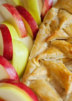 an apple pie with sliced apples in the background