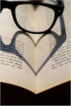 the shadow of a heart shaped book with glasses on it's face is shown in black and white