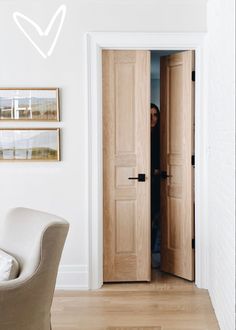 an open door in a living room with a chair and pictures on the wall behind it