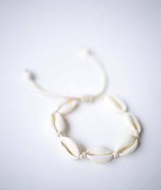 a white bracelet with seashells is shown on a white surface, it looks like something from the ocean