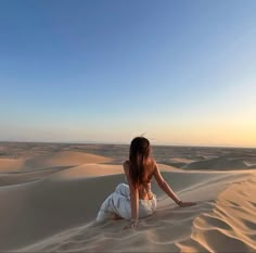 a woman sitting on top of a sandy dune