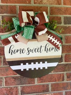 a football themed door hanger with the words home sweet home on it and a bow