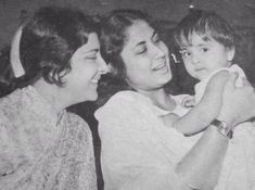 an old black and white photo of two women holding a child