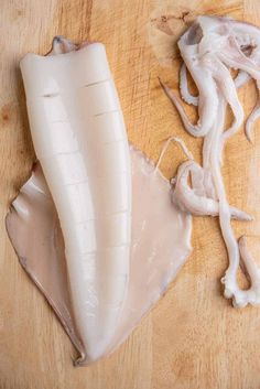 an uncooked squid on a cutting board next to it's skin and cloves