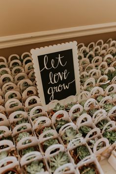 a box filled with lots of succulents next to a sign that says let love grow