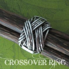 a cross ring sitting on top of a piece of wood in front of a green background