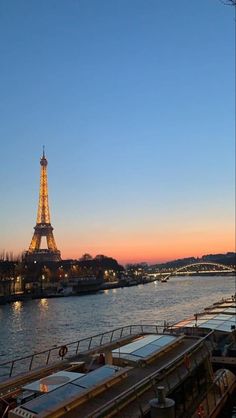 the eiffel tower is lit up at night next to boats docked in the water