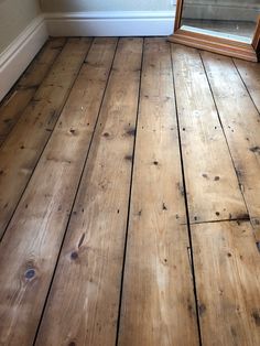 an empty room with wood flooring and a mirror on the wall next to it