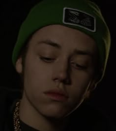 a young man wearing a green beanie with his eyes closed