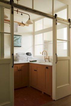 an open door leading to a kitchen with wooden cabinets and white towels on the counter