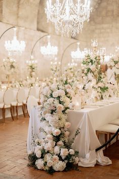 a table with white flowers and chandelier hanging from it's centerpiece