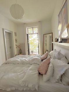 a bed with white sheets and pillows in a bedroom next to a doorway that leads to another room