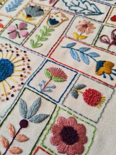 an embroidered table cloth with flowers and leaves on it