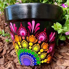 a painted flower pot sitting on the ground