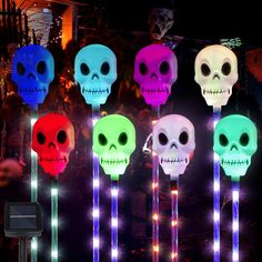 lighted skull heads on sticks are displayed in front of a dark room with other decorations