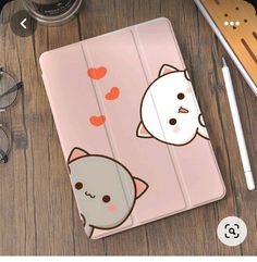 an ipad case with two cats and hearts on the cover, sitting on a wooden table