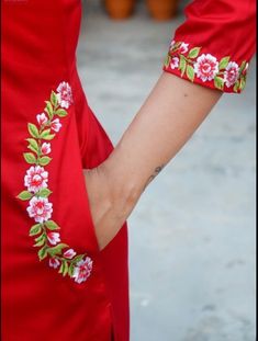 the woman is wearing a red dress with pink flowers on it and has her arm around another woman's waist