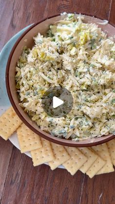 a bowl filled with coleslaw and crackers on top of a wooden table