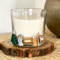 a glass candle holder with nativity figurines on it sitting on a table