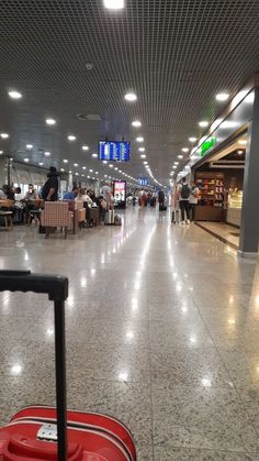 a red suitcase sitting in the middle of an airport