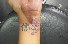 a woman's hand with a small tattoo on it and the word love written in chinese